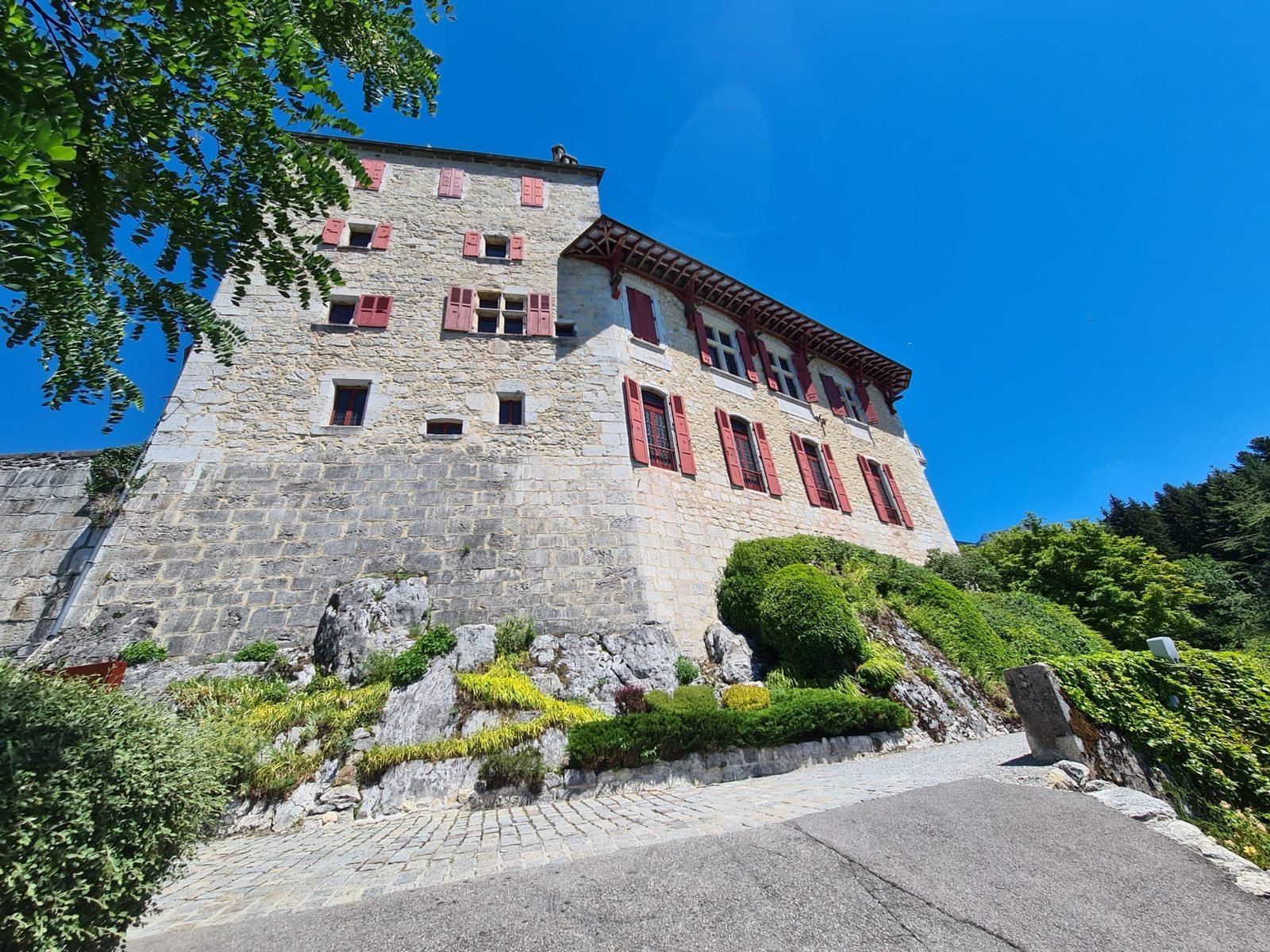 Façade du Château de Menthon-Saint-Bernard aux volets rouges
