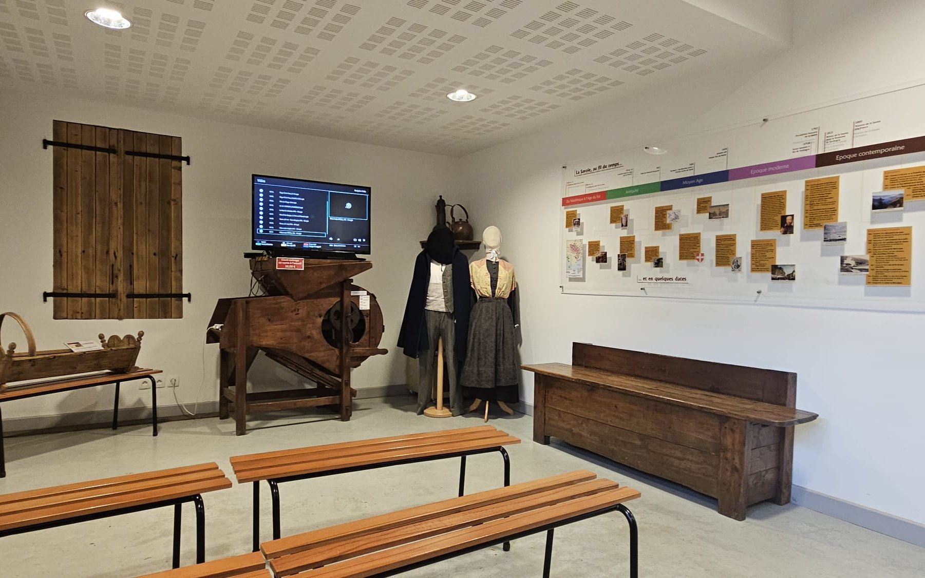 Salle d'exposition de l'Écomusée du Lac d'Annecy : frise « La Savoie au fil du temps », tarare et costumes savoyards