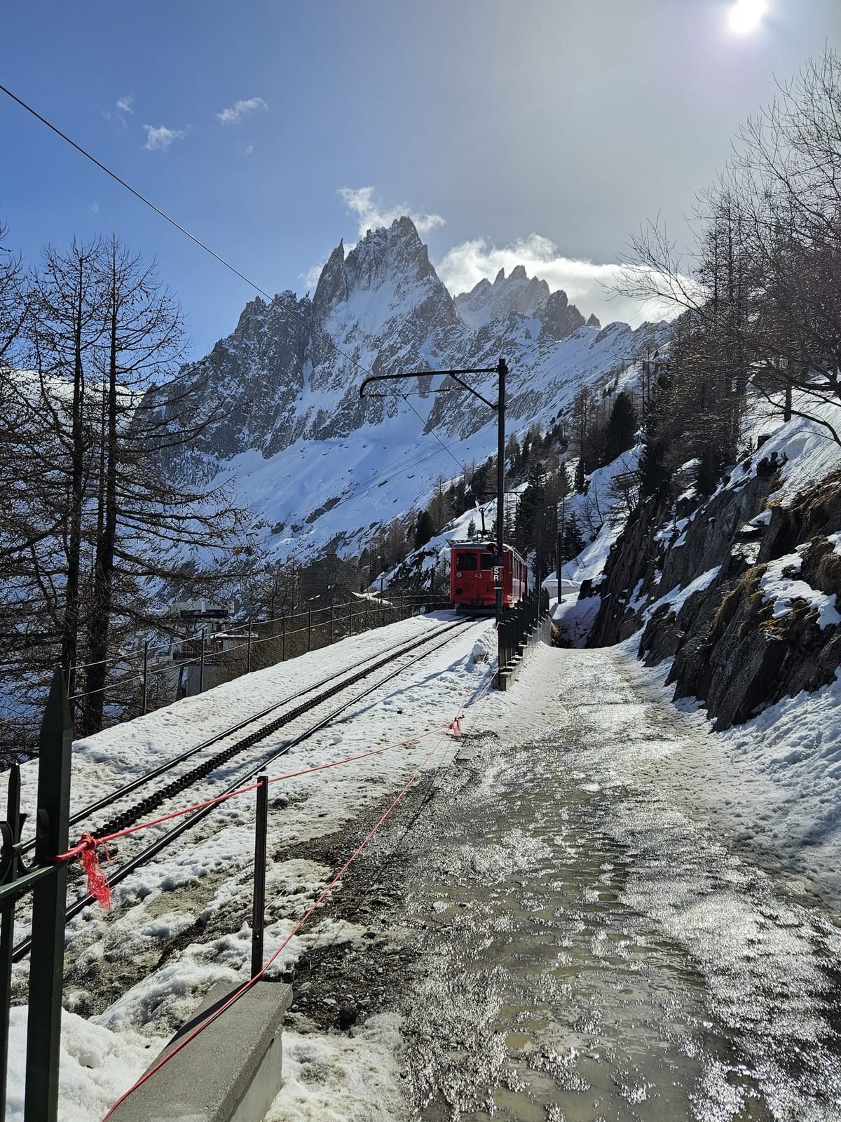 Train rouge du Montenvers montant vers la Mer de Glace en hiver, aiguilles de Chamonix dans les nuages