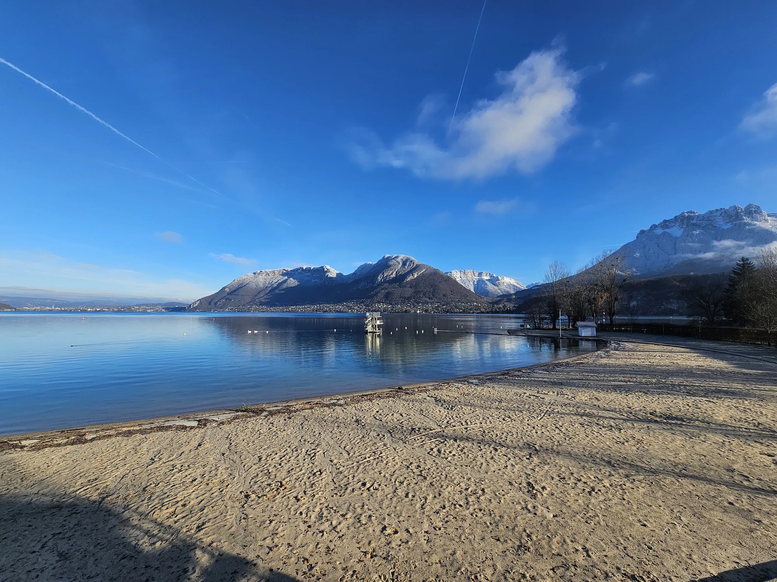 Plage de Saint-Jorioz au bord du lac d'Annecy avec sable naturel, pelouses et vue sur les Dents de Lanfon et la Tournette